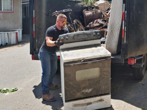Loading an old oven into a dumpster trailer