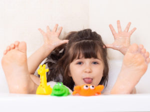 Sassy little girl in a bubble bath with tub toys in Conroe Texas