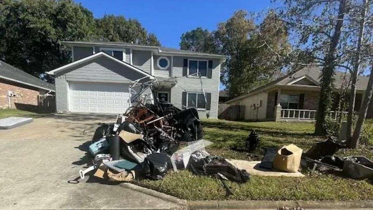 Storm debris, broken furniture and bagged yard waste piled on a driveway for junk removal pickup